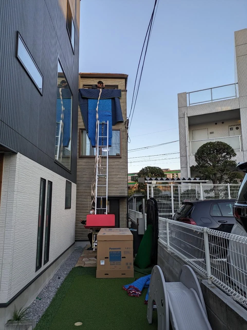 A moving crew carrying boxes and furniture out of a room protected with covering