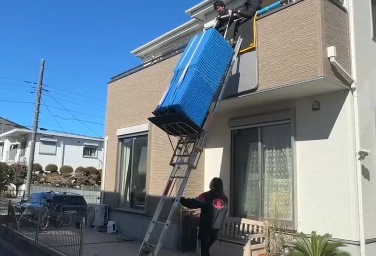 Staff installing a powered ladder along the exterior wall to bring a large piece of furniture to the second floor