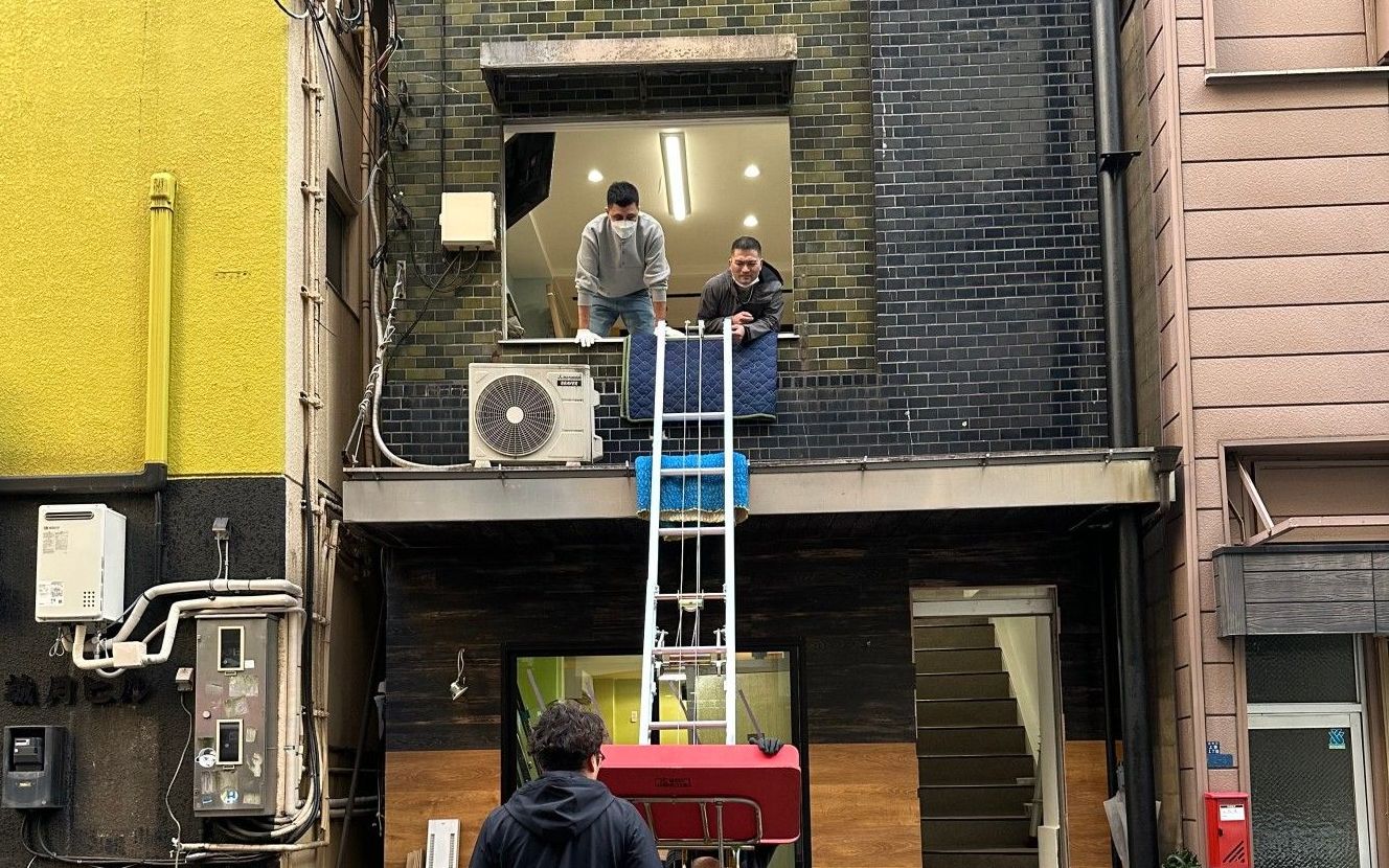 電動はしごとリフトを使い、建物二階の窓から荷物を搬入する作業員たち