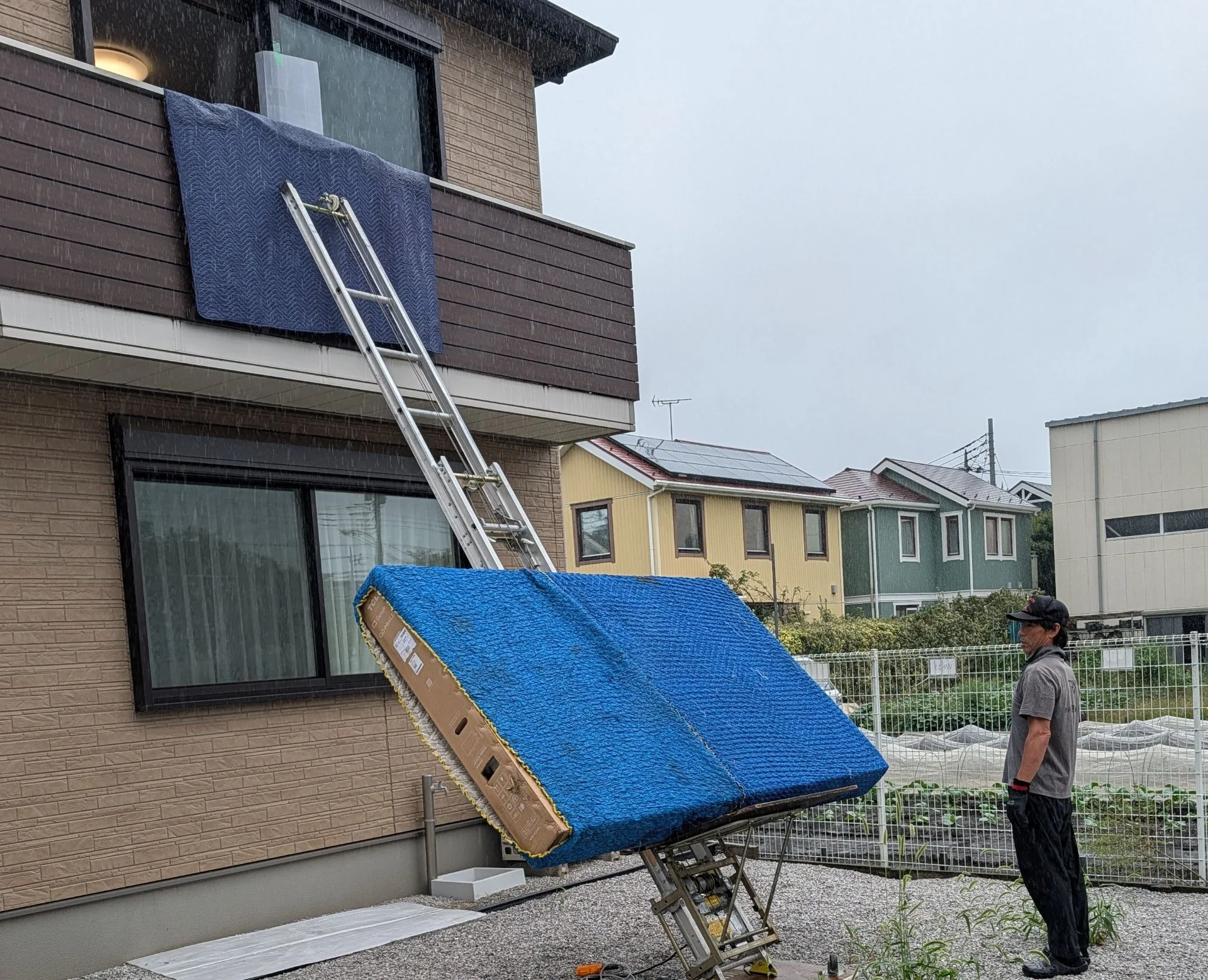 Workers using a powered ladder and lift to bring items in through a second-floor window