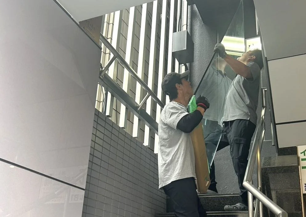 Workers carefully carrying a glass piece of furniture up a stair landing together