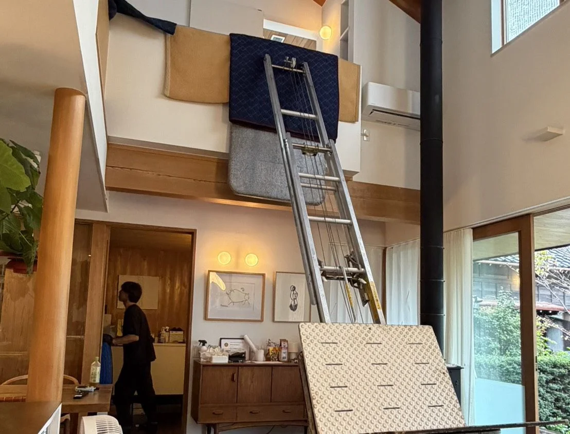 Workers bringing items to an upper floor of a home with an open stairwell using a protected powered ladder