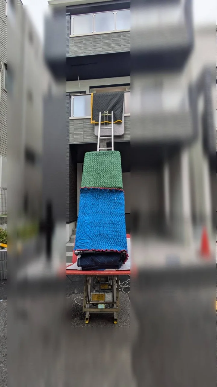 建物の外から搬入リフトで大型家具を上階へ運ぶ引越し作業